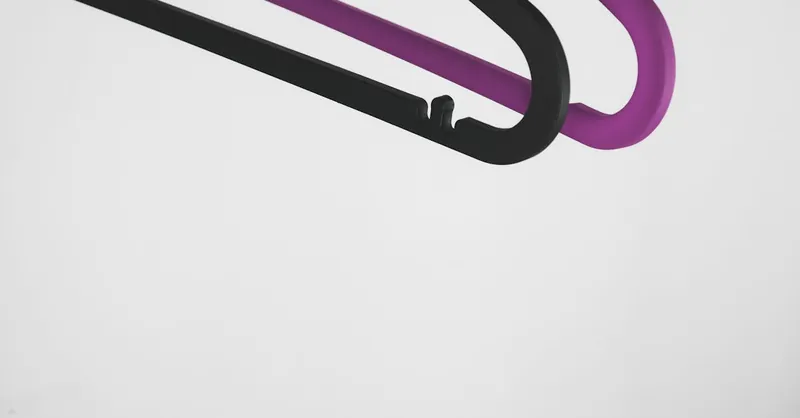 A minimalist photo of black and purple clothes hangers against a white background, emphasizing design and simplicity.