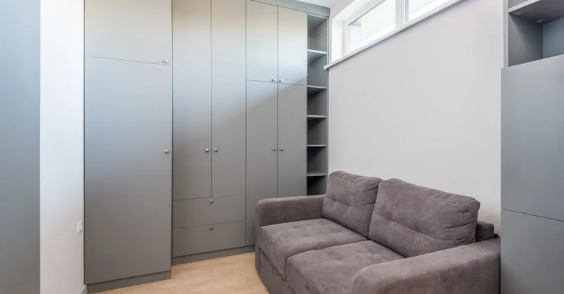 Sleek and modern apartment interior featuring grey wardrobe and sofa, ideal for space-saving living.