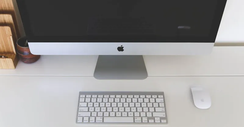 Minimalist home office workspace featuring a desktop computer, keyboard, and mouse on a white desk.