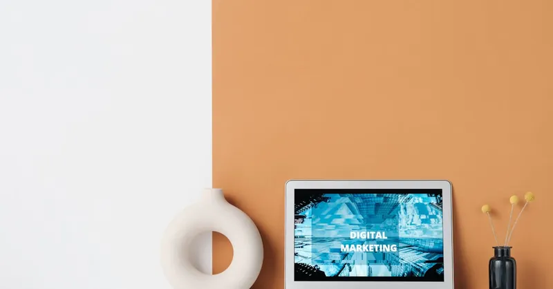 Minimalist workspace featuring a laptop with digital marketing text, a ceramic vase, and dried grass.