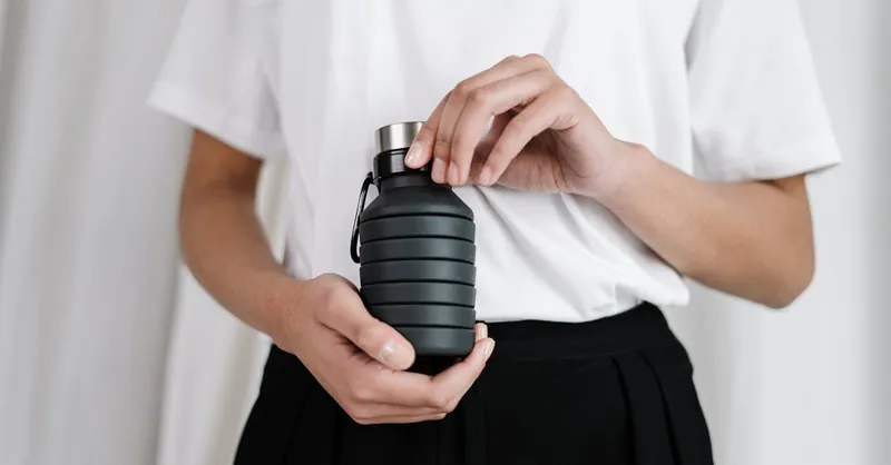A person holding a collapsible black water bottle, promoting zero waste lifestyle.