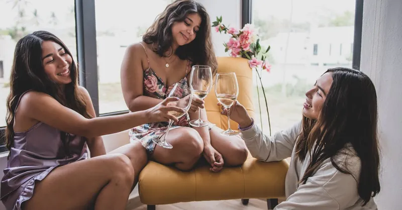 Three women enjoying drinks and conversation in a cozy indoor setting, celebrating friendship with wine.