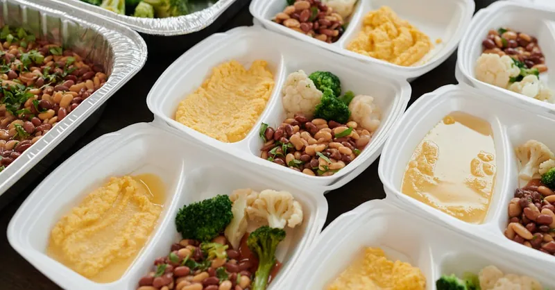 Assorted meal prep containers with beans, broccoli, and mashed potatoes, perfect for healthy eating.