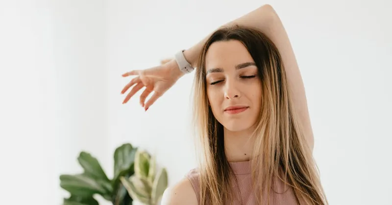 A peaceful young woman practicing mindfulness and yoga indoors with closed eyes, enjoying the calm atmosphere.