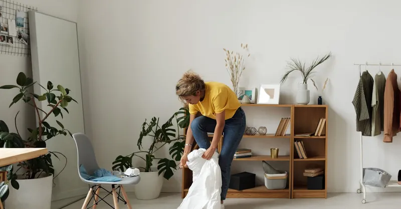 A woman tidying up a chic, minimalist living room with natural decor and modern furniture.