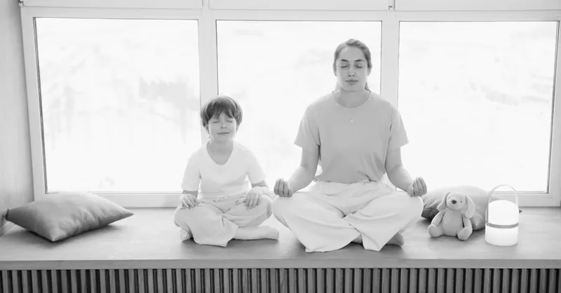 Mother and son practicing meditation, sharing a peaceful moment in a sunlit room.