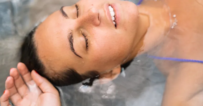Close-up of a relaxed woman floating in water with eyes closed and enjoying serene moment.