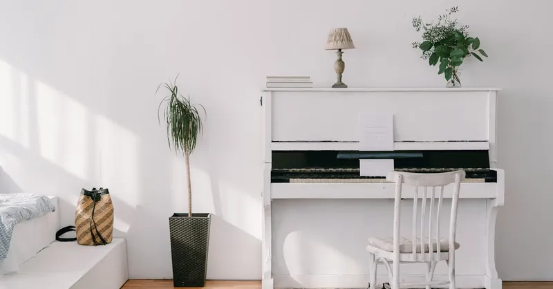 Elegant minimalist interior featuring a white upright piano, green plants, and natural light.