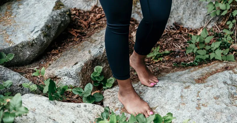 Person standing barefoot on natural rocks, connecting with nature, emphasizing grounding and mindfulness.