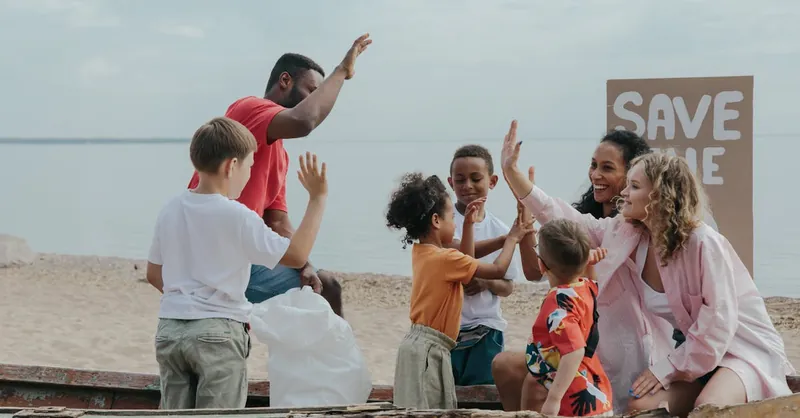 A diverse group of people enjoying a beach cleanup, promoting