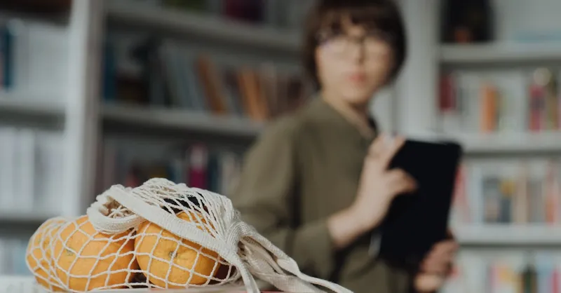Eco-friendly shopping concept with oranges in a string bag and a blurred shopper in a library setting.