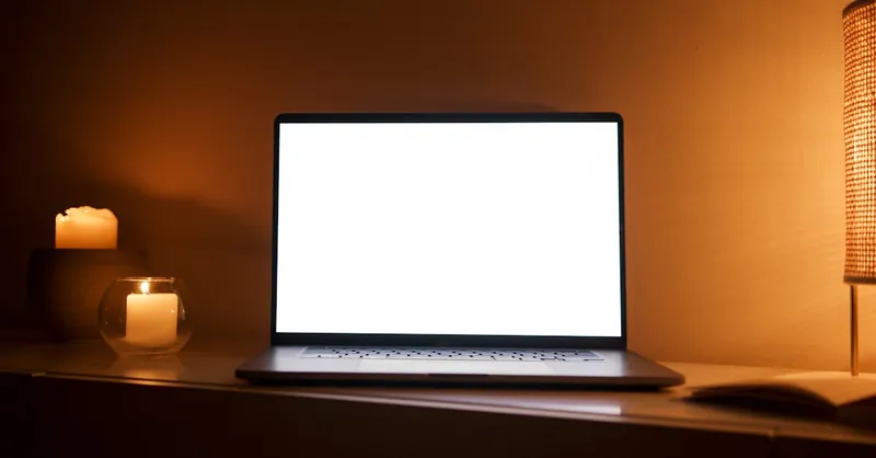 A warm-toned workspace with a laptop and lit candles, perfect for relaxation or work.