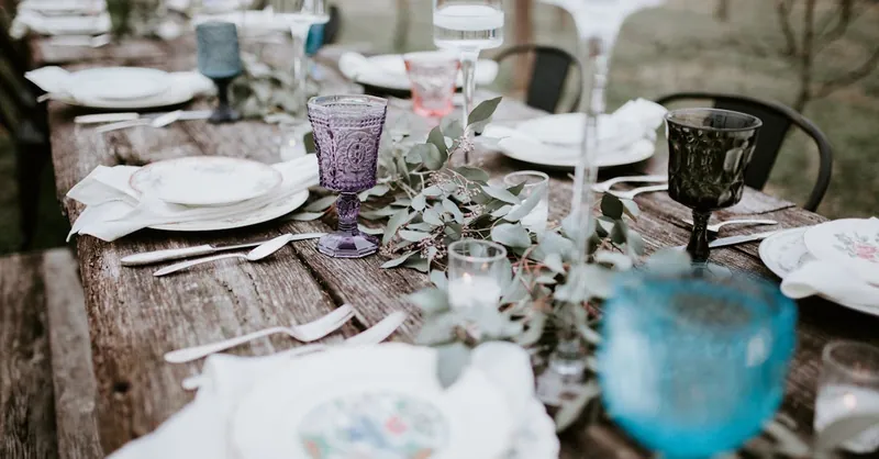 Elegant rustic outdoor wedding table setup with vintage glassware and greenery.