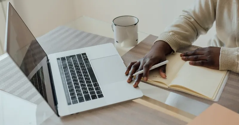 A minimalist workspace featuring a laptop, journal, and pen, perfect for remote work.