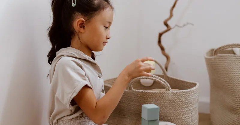 A young girl organizing toys in a basket, creating a tidy and peaceful home environment.