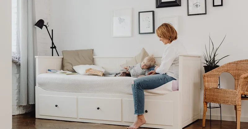 A mother and child bonding in a cozy, minimalist bedroom setting.