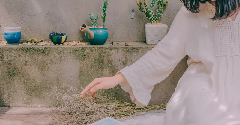 Peaceful setting of a woman with book, succulents, and dried flowers in natural light.