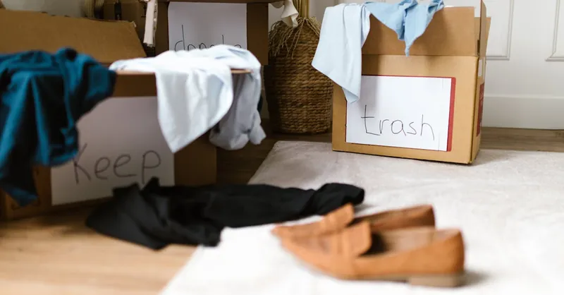 Decluttering concept using labeled boxes for sorting clothes in a home setting.