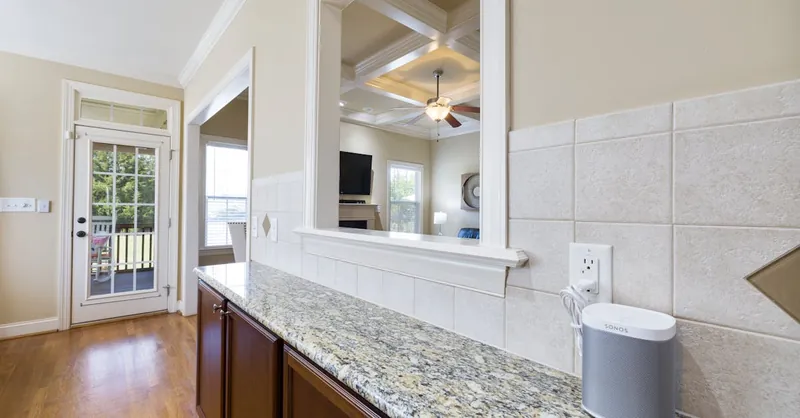 Bright kitchen space featuring granite countertops, coffered ceiling, and contemporary decor.