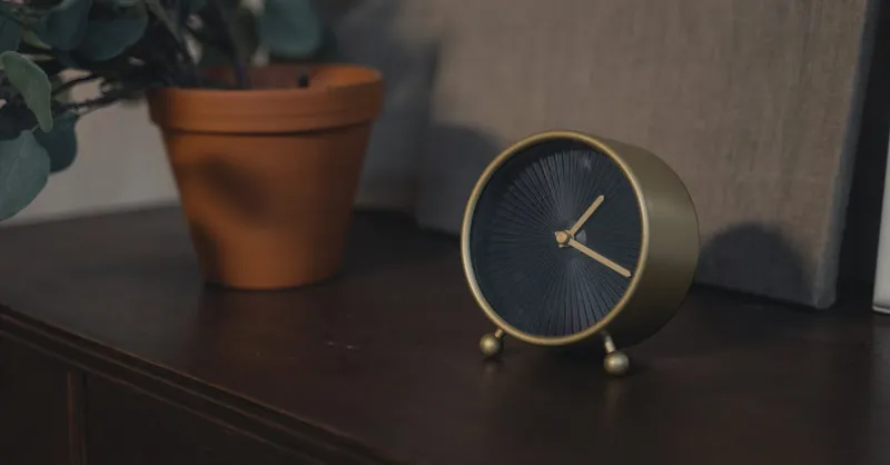 Stylish minimalist clock and potted plant on wooden table, perfect for decor inspiration.