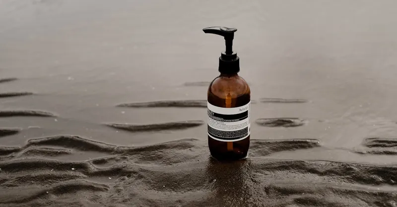 Minimalist image of a skincare bottle placed on a wet sandy beach, emphasizing tranquility.
