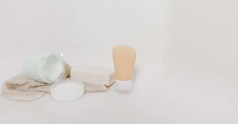 Minimalist setup of skincare products including cream, soap, and lotion on a white surface for beauty and self-care themes.