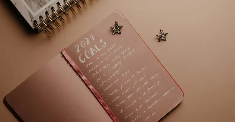 Top view of a 2021 goals notebook with handwritten list and star decorations, ideal for planning inspiration.