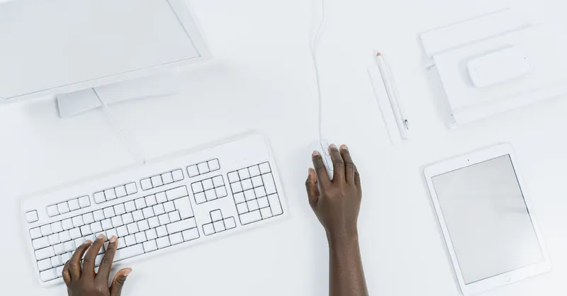 Top view of a minimalist workspace with a computer, keyboard, and tablet.