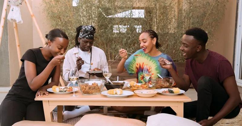 A joyful group of friends enjoying a meal together outdoors, showcasing diversity and friendship.